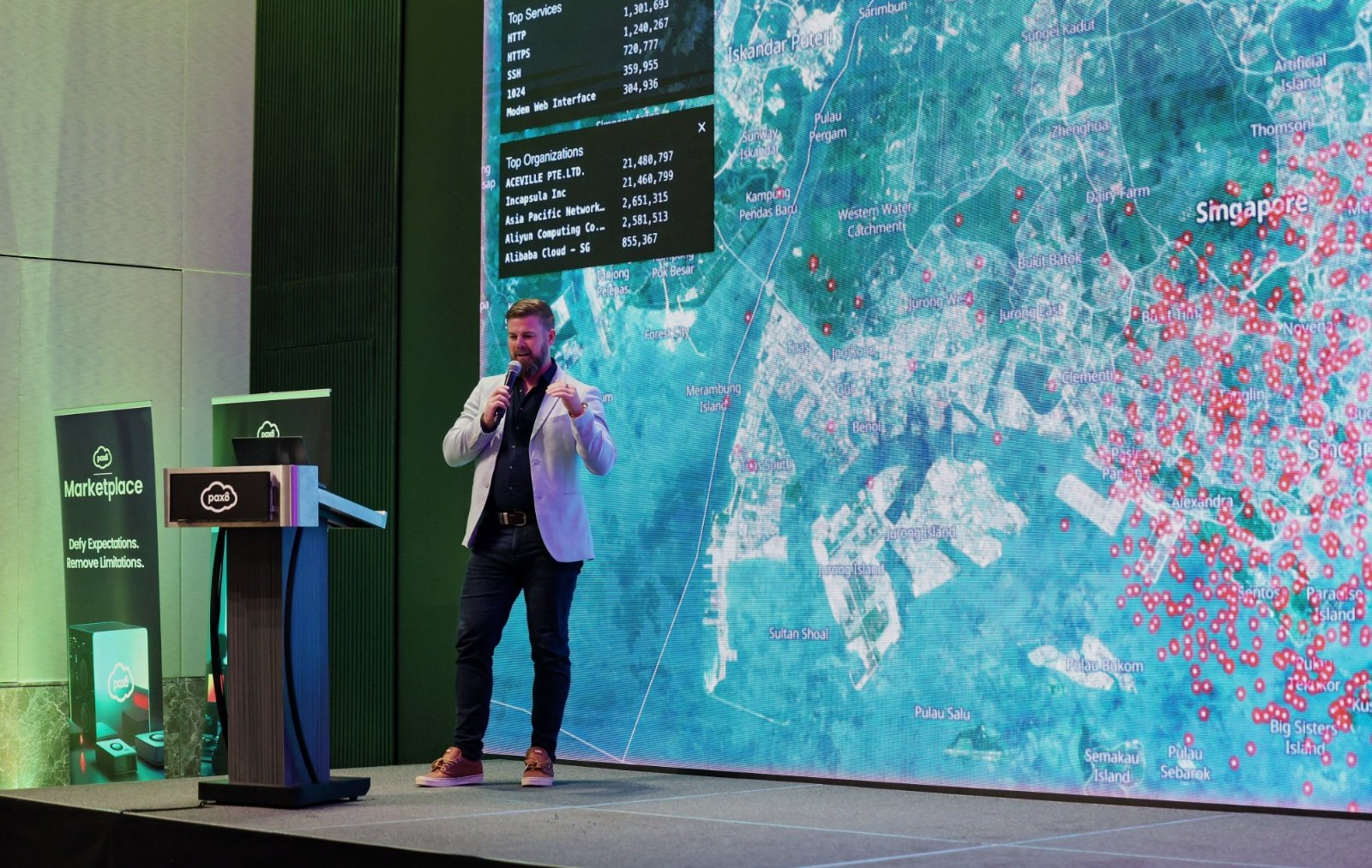 Adam Green on stage in front of a live external exposure map of Singapore, covered in red dots